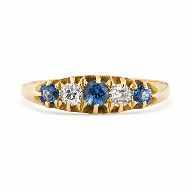 An antique, Edwardian blue sapphire & diamond five-stone ring in yellow gold.