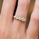 An antique Victorian old-mine cut diamond five-stone engagement ring in yellow gold, shown on a finger.