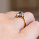 A vintage blue sapphire & diamond cluster ring in yellow gold with an open back shown from the side.