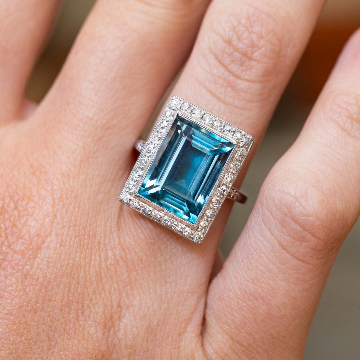 An antique Art Deco aquamarine and diamond cocktail ring in platinum worn on the finger.