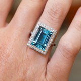 An antique Art Deco aquamarine and diamond cocktail ring in platinum worn on the finger.