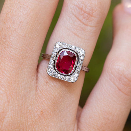 An antique Art Deco red spinel and diamond cluster ring worn on the finger.