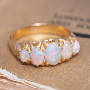 An antique, Victorian precious white opal five-stone ring showing motifs and scrollwork.