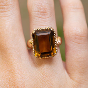 A close-up of a vintage 1970s Cartier smoky quartz cocktail ring worn on the finger.