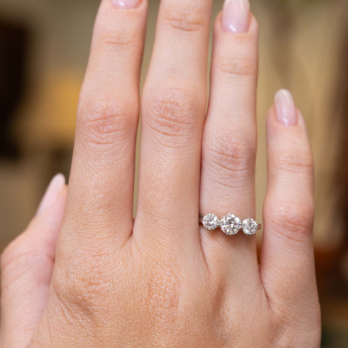 Edwardian diamond three-stone engagement ring shown at full scale on the hand