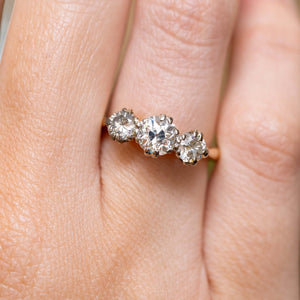 A close-up of three graduated old-cut diamonds in claw settings worn on the finger.