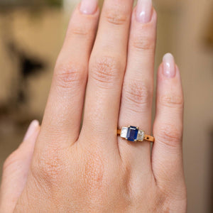 Sapphire and diamond three-stone engagement ring shown at full scale on the hand