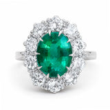 A vintage, 1950s oval emerald and diamond cluster engagement ring set in white gold.
