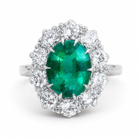 A vintage, 1950s oval emerald and diamond cluster engagement ring set in white gold.