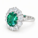 A three-quarter of a vintage, 1950s oval emerald and diamond halo cluster engagement ring set in 18ct white gold.