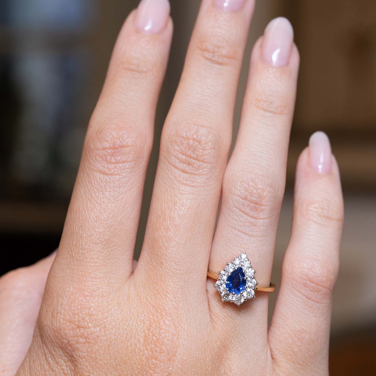 Pear-shaped sapphire and diamond cluster ring shown at full scale on the hand