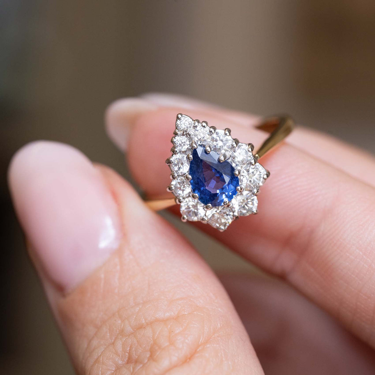 Close-up of a blue sapphire surrounded by a pear-shaped diamond halo