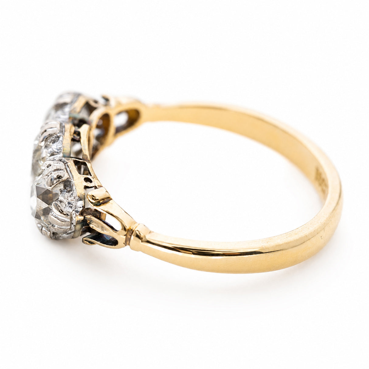 an Angled view of a Victorian three-stone diamond ring with a yellow gold band