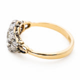 an Angled view of a Victorian three-stone diamond ring with a yellow gold band