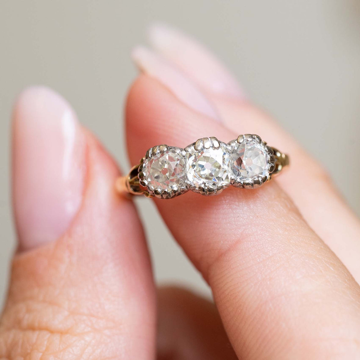 Close-up of an antique Victorian diamond engagement ring held on the finger