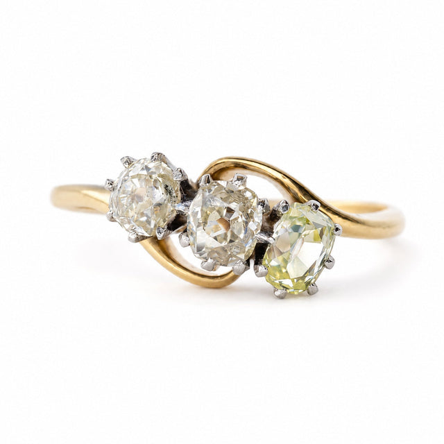 An Antique Art Nouveau diamond three-stone engagement ring with flowing gold shoulders