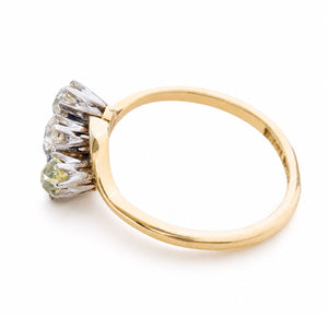 Angled view of an Art Nouveau three-stone diamond ring in yellow gold