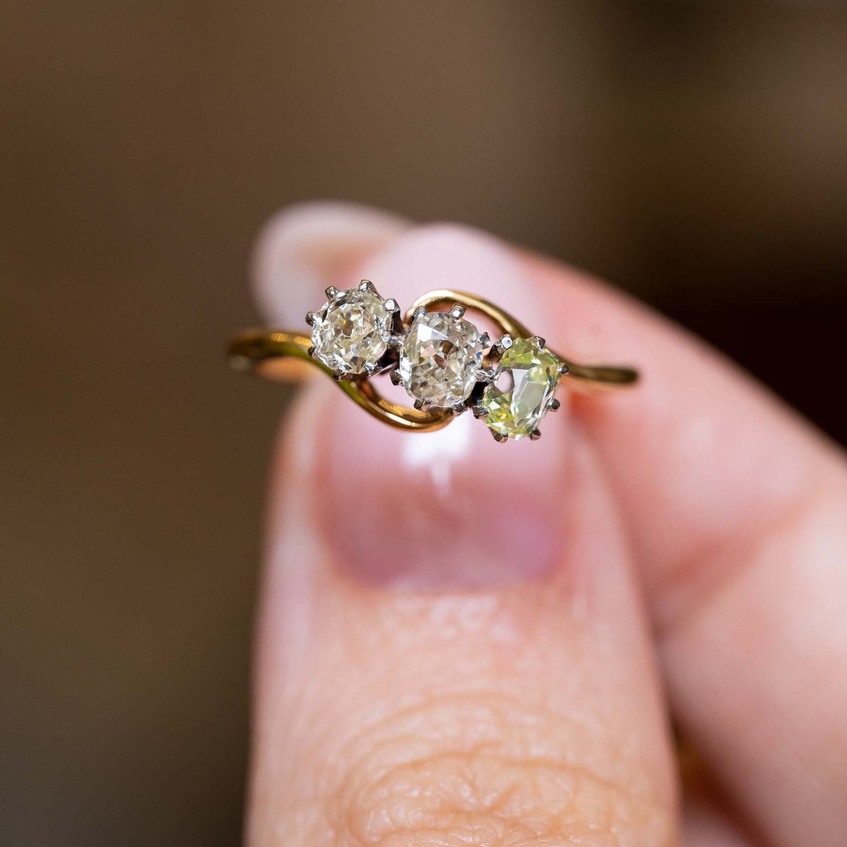 Close-up of art nouveau ring with three characterful antique diamonds and sinuous gold detailing