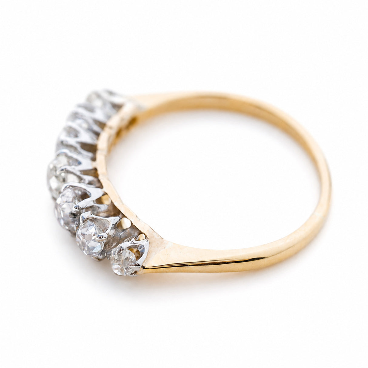 Angled view of an Edwardian seven-stone diamond ring with a yellow gold band