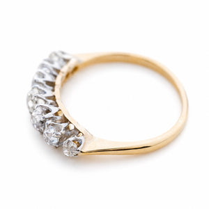 Angled view of an Edwardian seven-stone diamond ring with a yellow gold band