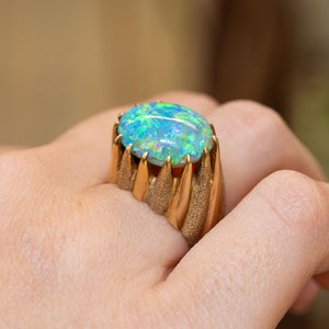 A close-up of a vintage 1970s cabochon Australian opal ring worn on the hand.