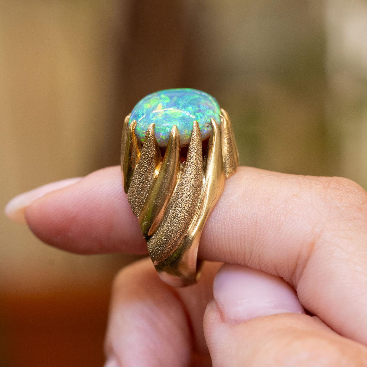 Detail of a vintage cabochon Australian opal ring highlighting the sculptural yellow gold band.
