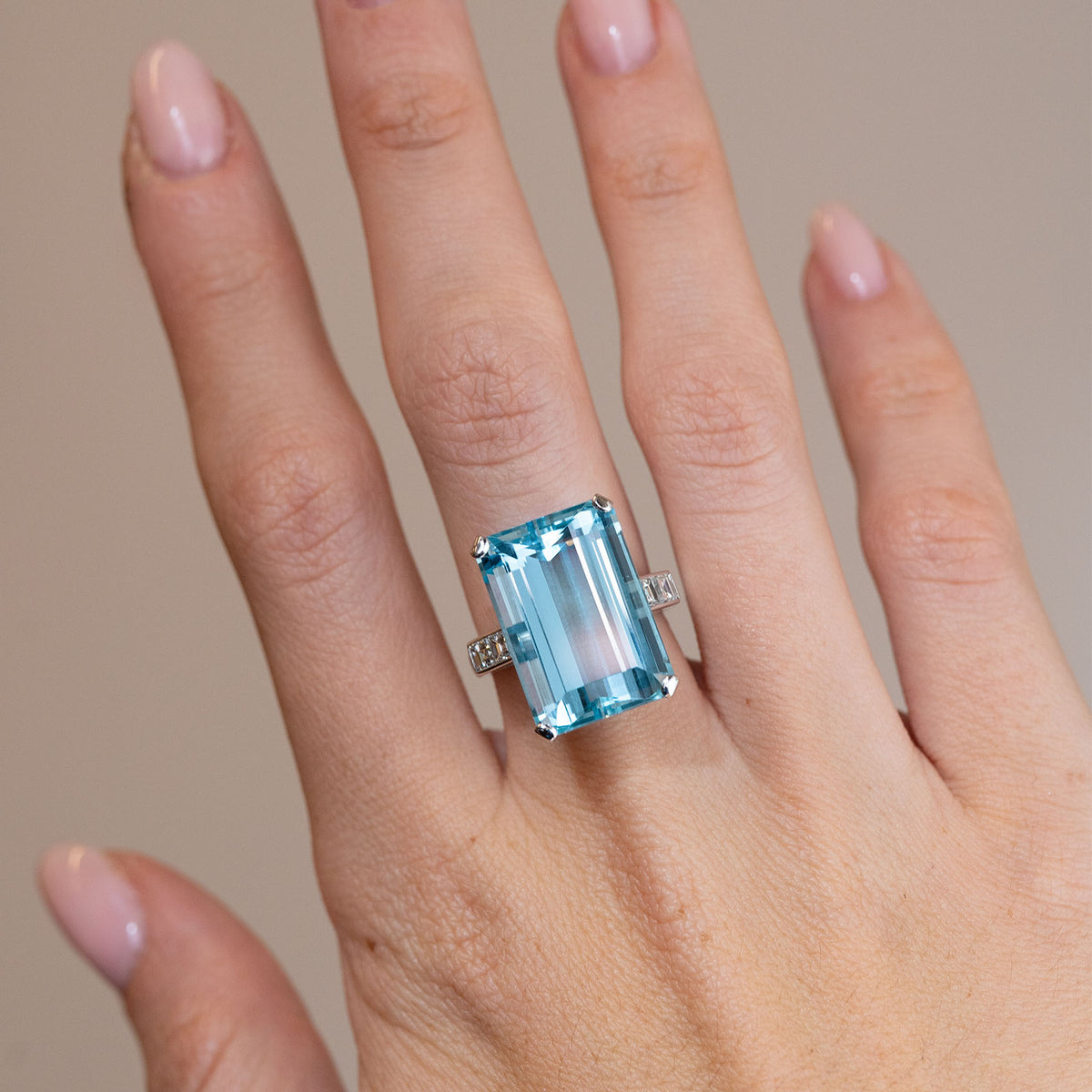 Vintage 1970s aquamarine and diamond cocktail ring worn on a hand, displaying its striking rectangular blue gemstone and polished white gold band.