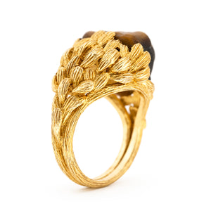 A photo of the side of a Vintage, 1980's French tiger's eye honey bear ring in carved yellow gold on a plain white background