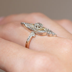 Side profile of an antique Art Nouveau diamond cross-over ring worn on the finger, displaying its raised setting and sculptural design.