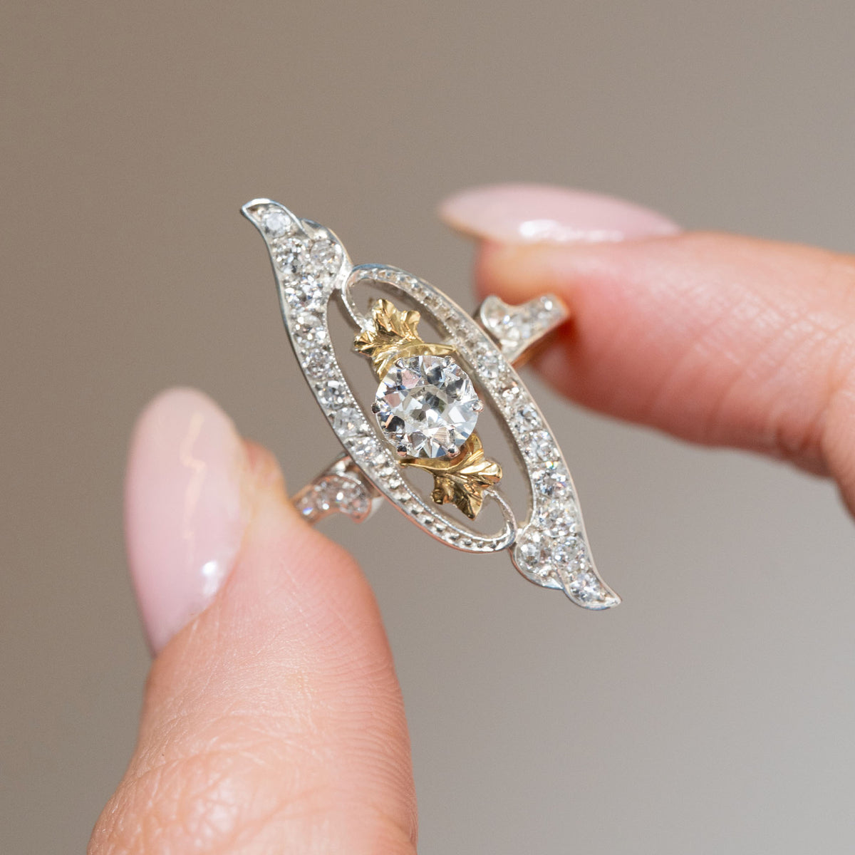 Detailed view of an antique Art Nouveau diamond cross-over ring, highlighting the old-cut centre diamond and decorative diamond-set platinum scrollwork.