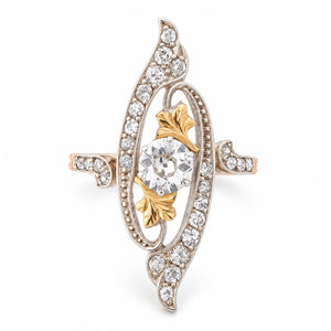 Antique Art Nouveau diamond cross-over ring in yellow gold and platinum, featuring an old-cut diamond within an ornate diamond-set swirling design.