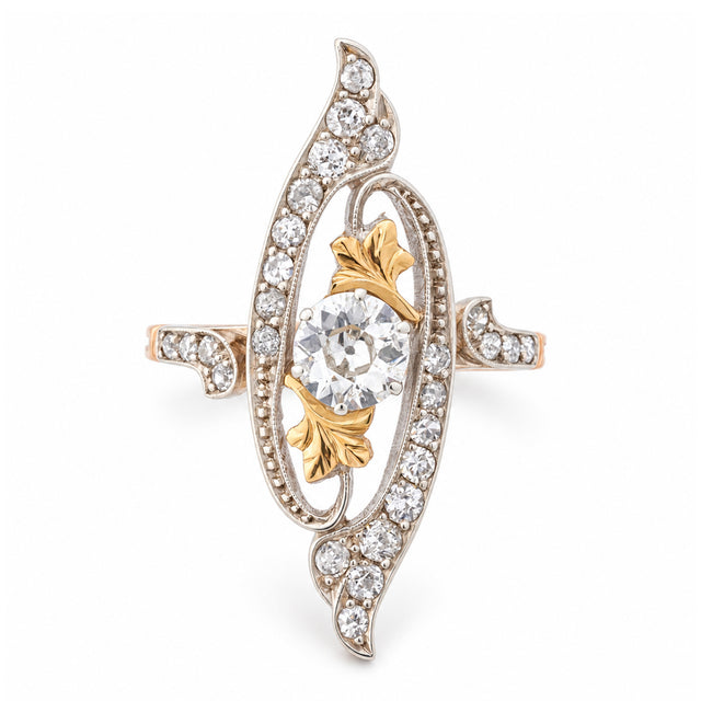 Antique Art Nouveau diamond cross-over ring in yellow gold and platinum, featuring an old-cut diamond within an ornate diamond-set swirling design.