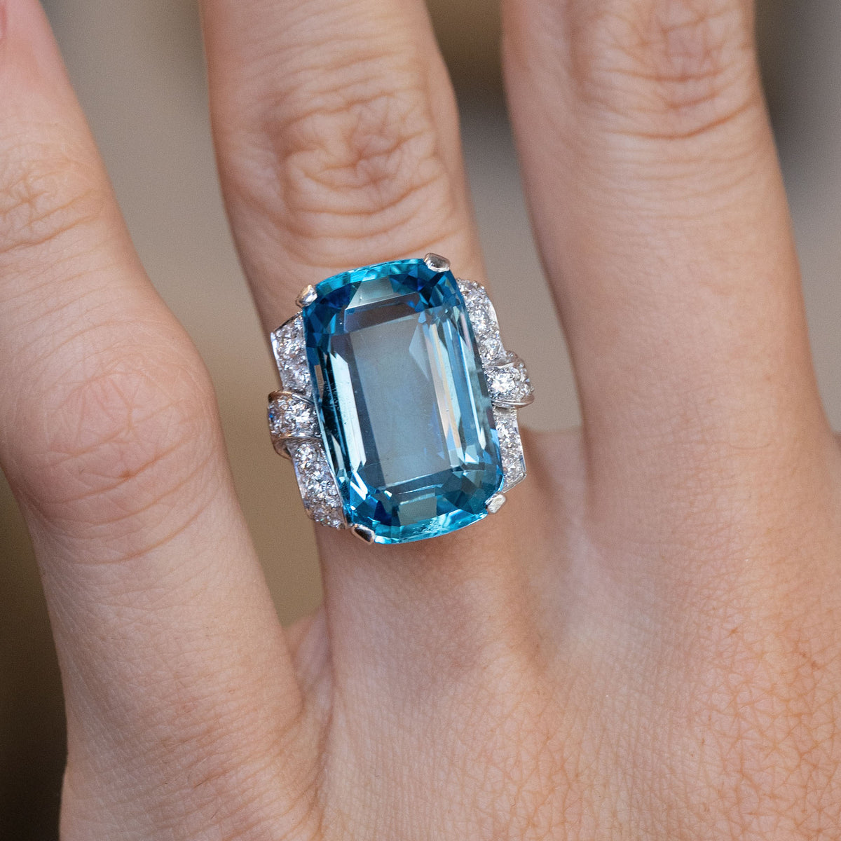 Art Deco aquamarine and diamond cocktail ring worn on a finger, highlighting the striking rectangular gemstone and bold design.