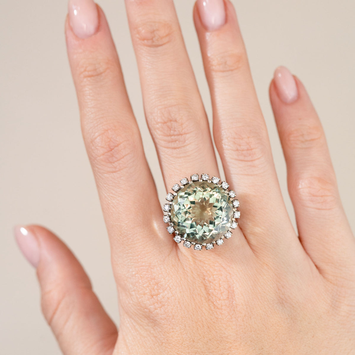 Green quartz statement ring worn on a hand, showcasing its impressive size and delicate diamond surround.