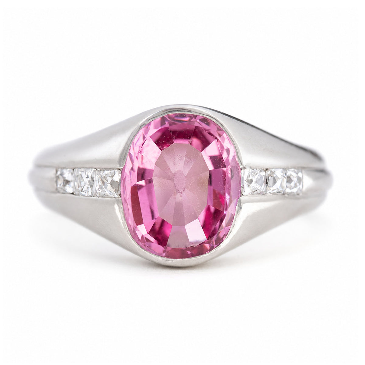 A vintage, 1940s pink sapphire and diamond gypsy ring in platinum on a white background