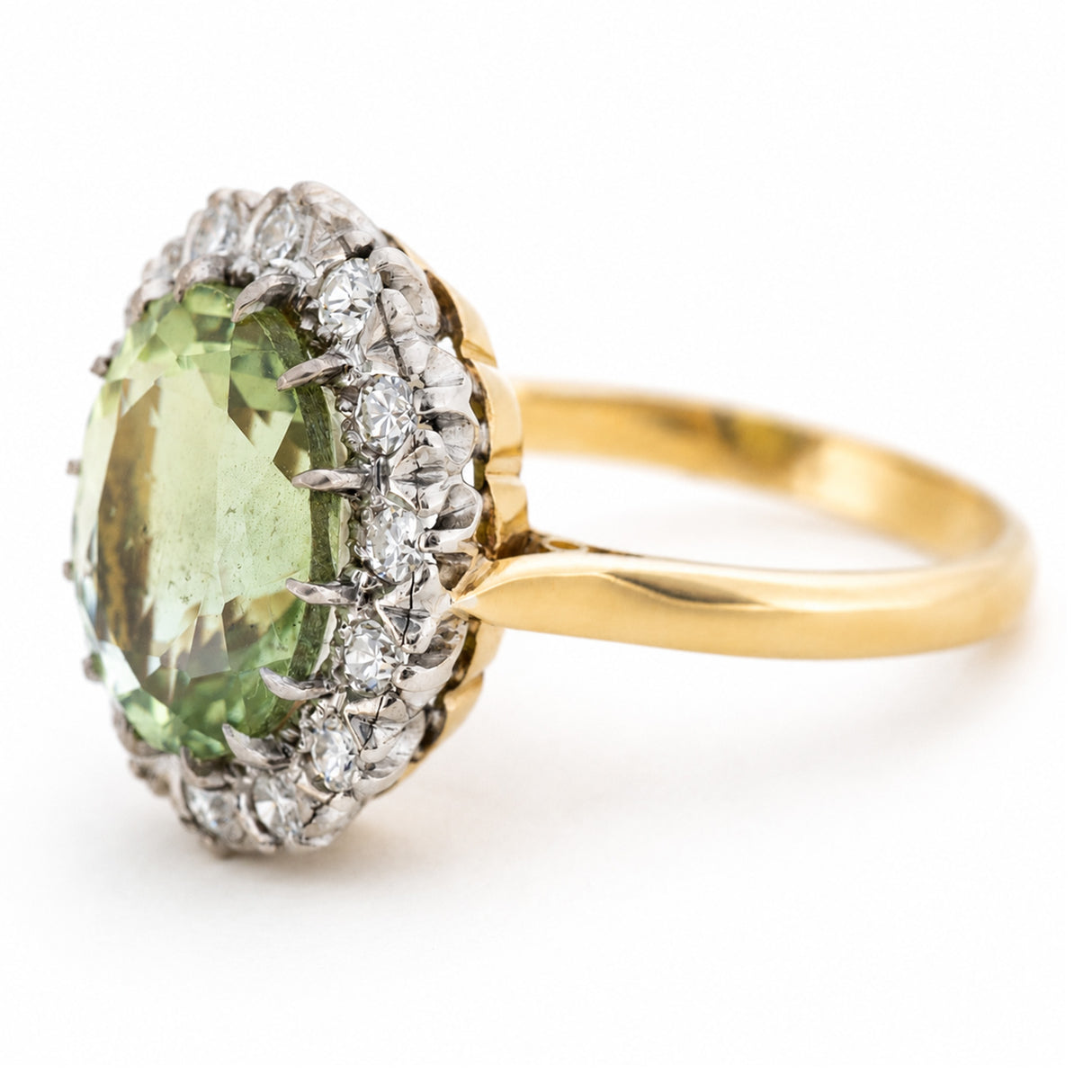 A Vintage 1950's yellow gold engagement ring featuring a large oval green beryl surrounded by a halo of diamonds, set on a plain white background.