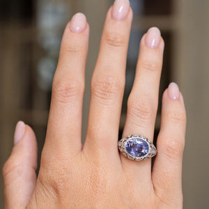a hand wearing an antique cocktail colour-change sapphire held at a distance to show proportions