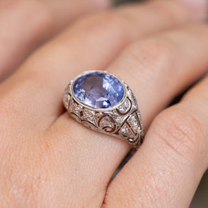 A hand wearing Antique, Belle Époque Ceylon colour-change sapphire and diamond cluster ring in platinum 