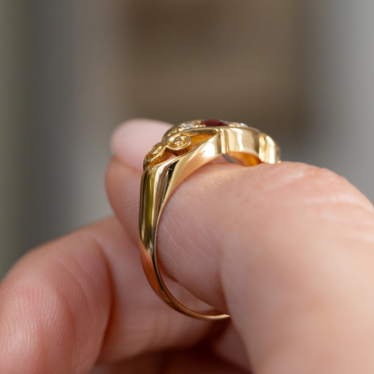 Rear three-quarter view of the antique ring, showing the polished yellow gold band and sculptural construction beneath the gemstones.