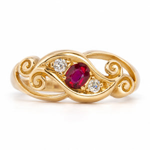 Antique Edwardian ruby and diamond three-stone ring in yellow gold, featuring a central ruby flanked by two diamonds within scrolling openwork.