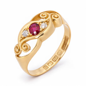 Elevated studio portrait of the Edwardian three-stone ring, revealing its ruby centre, diamond accents and ornate gold scrolls.