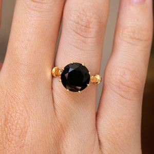 A close-up of a hand wearing a yellow gold Vintage 1980's green tourmaline cocktail ring, showcasing the dark green tourmaline stone and details on the yellow gold band. 
