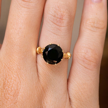 A close-up of a hand wearing a yellow gold Vintage 1980's green tourmaline cocktail ring, showcasing the dark green tourmaline stone and details on the yellow gold band. 