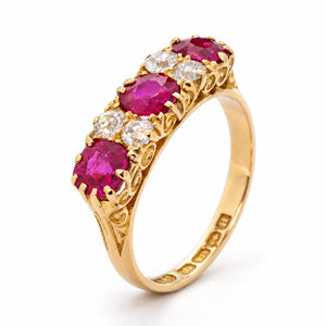 Elevated studio portrait of the Edwardian ruby ring, revealing its graduated gemstone arrangement and ornate pierced yellow gold gallery.