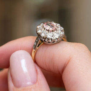 Vintage orange-pink sapphire and diamond cluster ring highlighting the raised cluster setting, diamond surround and mixed-metal mount.