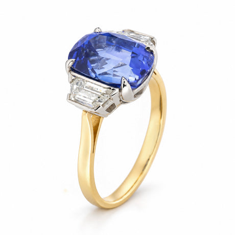 Angled studio view of the blue sapphire and diamond ring, showcasing its platinum claw settings and polished yellow gold band.