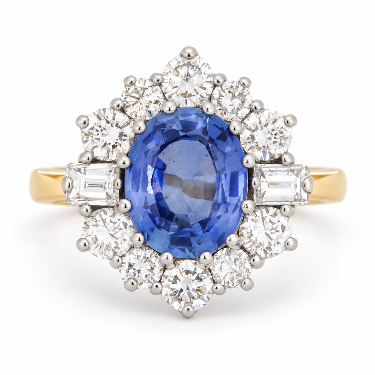 Vintage 1980s blue sapphire and diamond cluster ring in yellow gold and platinum, featuring an oval-cut blue sapphire surrounded by round brilliant-cut and baguette-cut diamonds.