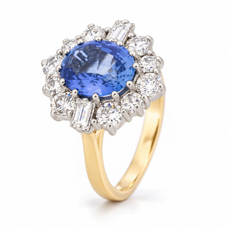 Angled view of a vintage 1980s blue sapphire and diamond cluster ring, showcasing its oval blue sapphire, intricate platinum diamond setting and polished yellow gold band.