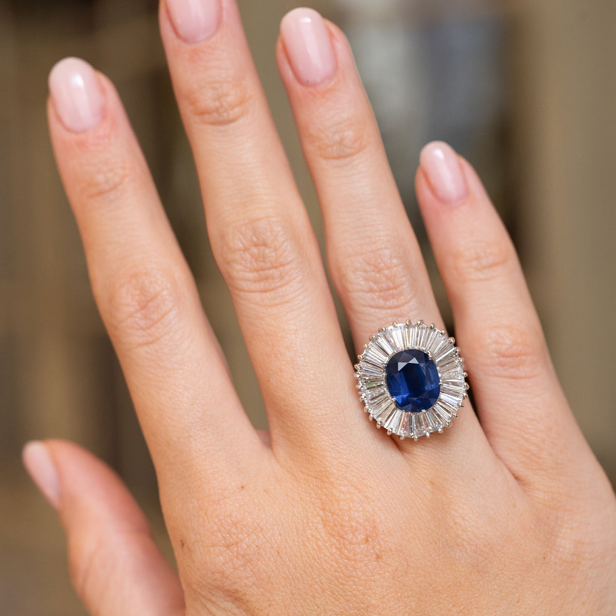 Vintage 1950s ballerina cluster ring worn on the hand, showcasing its blue sapphire centre and dramatic diamond surround. 