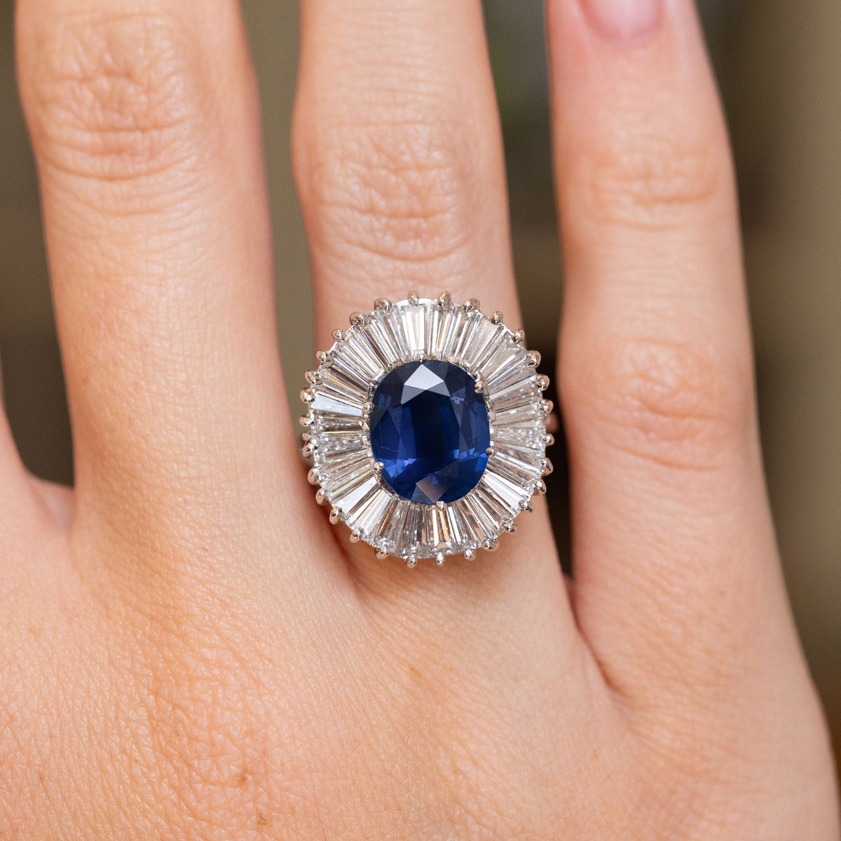 Close-up of a vintage 18ct white gold ring with a rich blue sapphire encircled by a fan of baguette-cut diamonds.